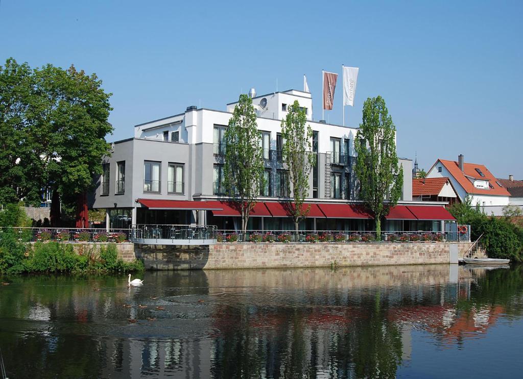 ein Gebäude an der Seite eines Wasserkörpers in der Unterkunft Hotel Eberhards am Wasser in Bietigheim-Bissingen