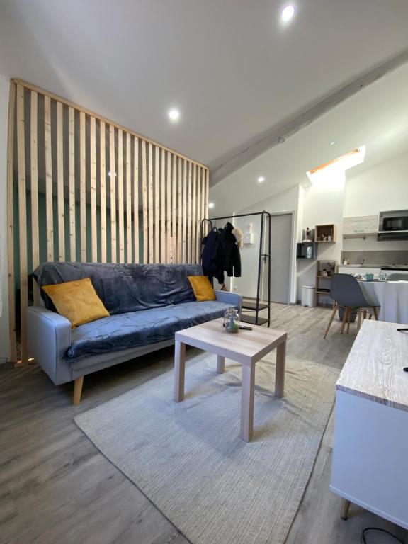 ein Wohnzimmer mit einem blauen Sofa und einem Tisch in der Unterkunft Appartement loft Manosque in Manosque