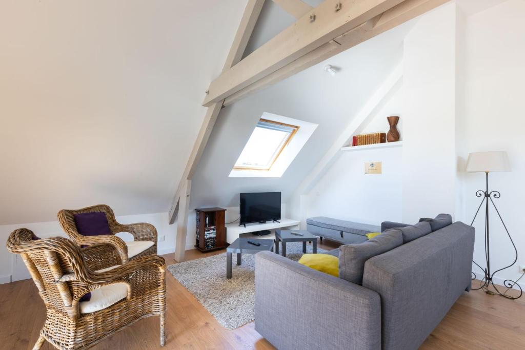 sala de estar con sofá, sillas y TV en Appartement des Grands Champs avec terrasse en Saint-Aignan