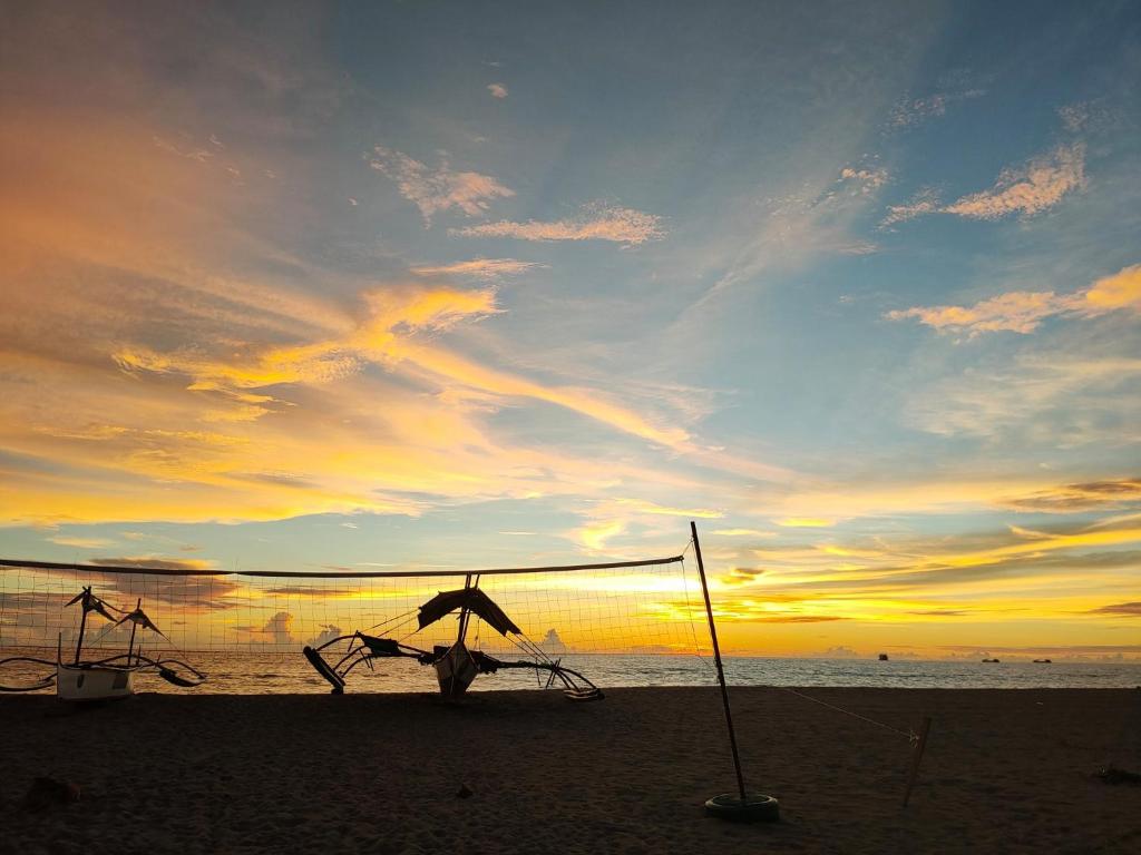 a sunset on the beach with an umbrella at Mope Beach Resort in San Narciso