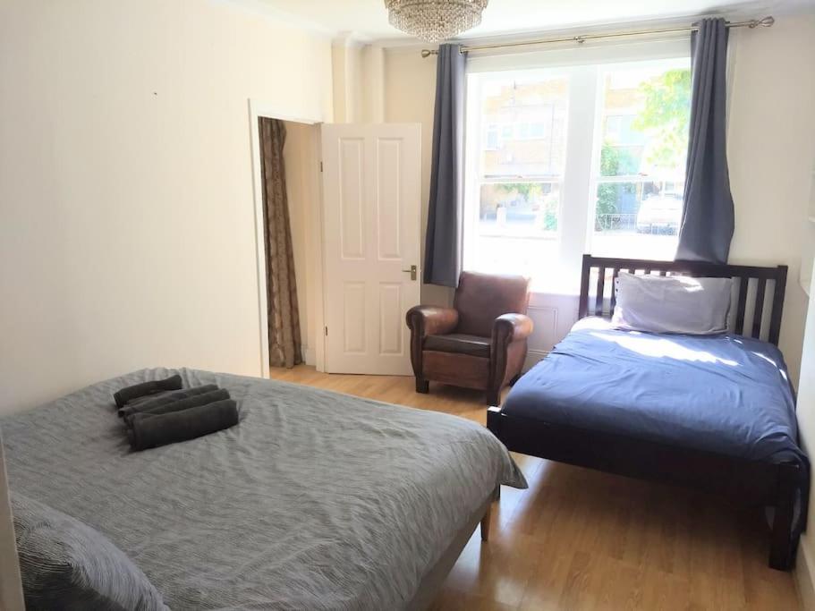 a bedroom with two beds and a chair and a window at Self-contained private apartment Unit 1 in London