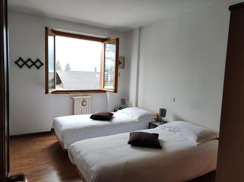 two beds in a room with a window at Baita nei pra in Bormio