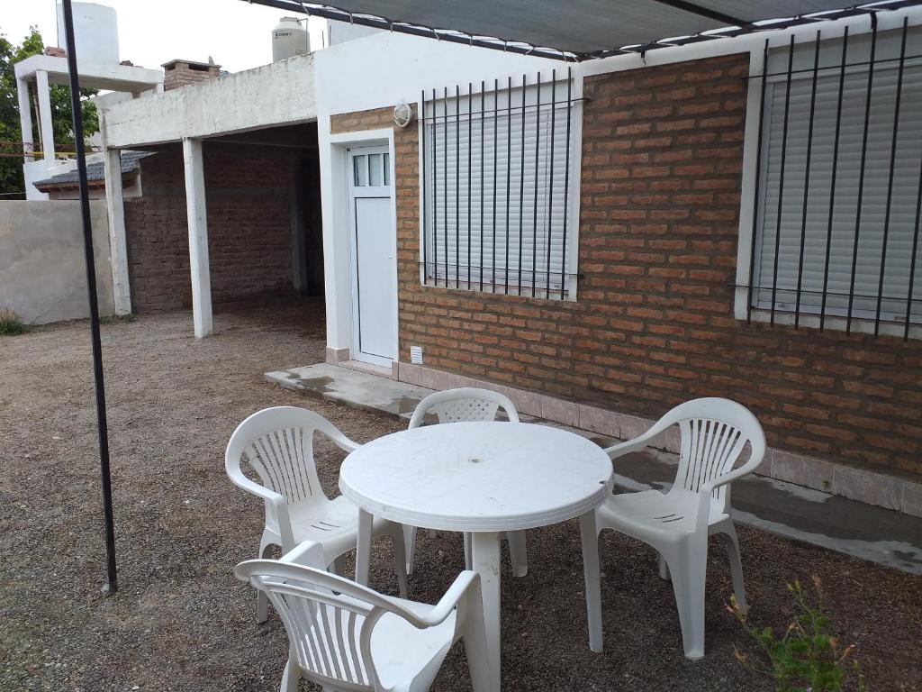 una mesa blanca y cuatro sillas blancas frente a un edificio de ladrillo en Dpto 4 personas en Las Grutas en Las Grutas