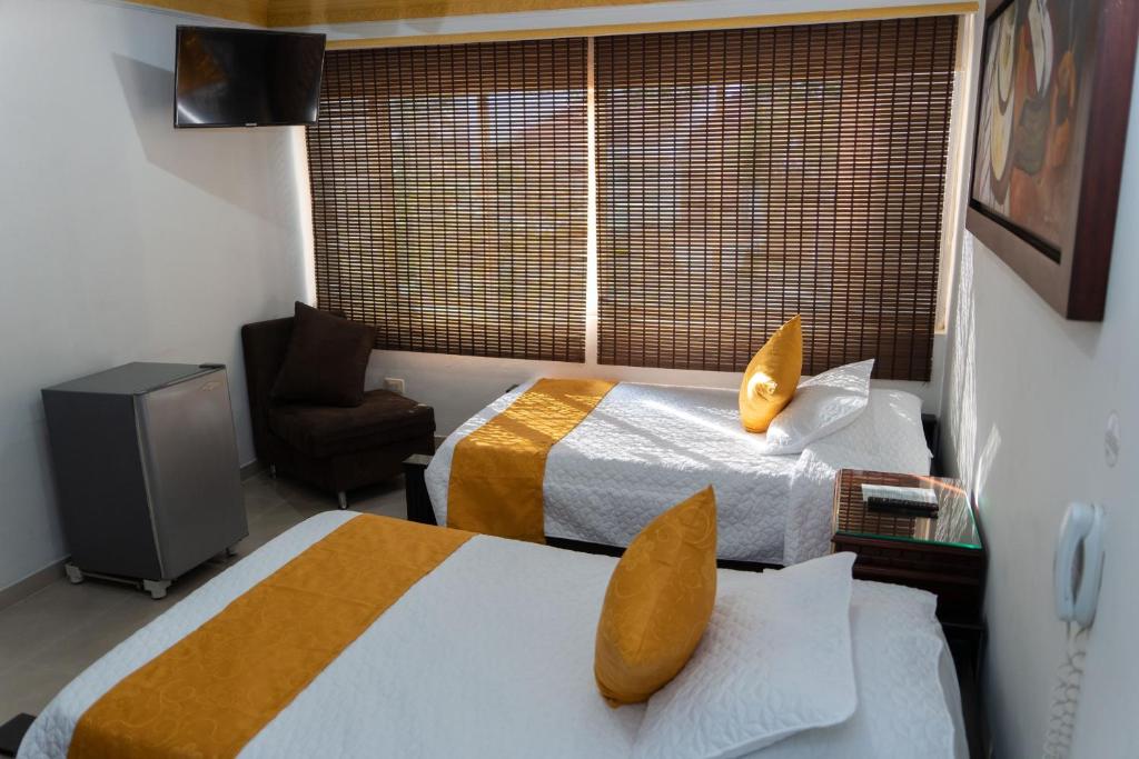 una habitación de hotel con 2 camas y una silla en Hotel Aires del Quindío Armenia, en Armenia