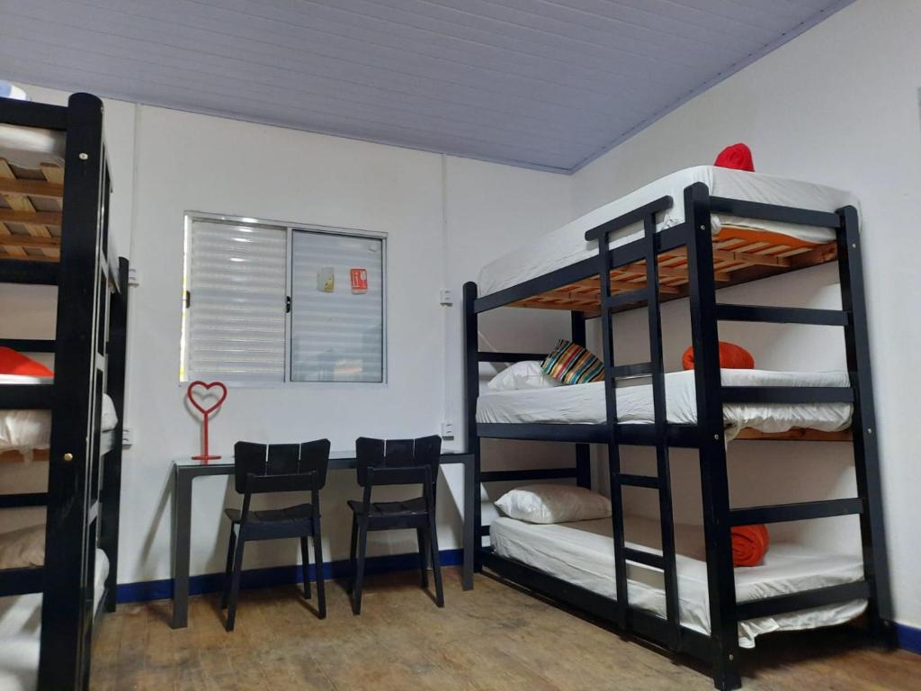 a room with bunk beds and a table and chairs at Vilarejo Hostel Pinheiros Guest House in Sao Paulo