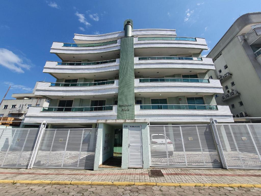 a tall building with a fence in front of it at Ótimo apartamento na praia de Bombas. in Bombinhas