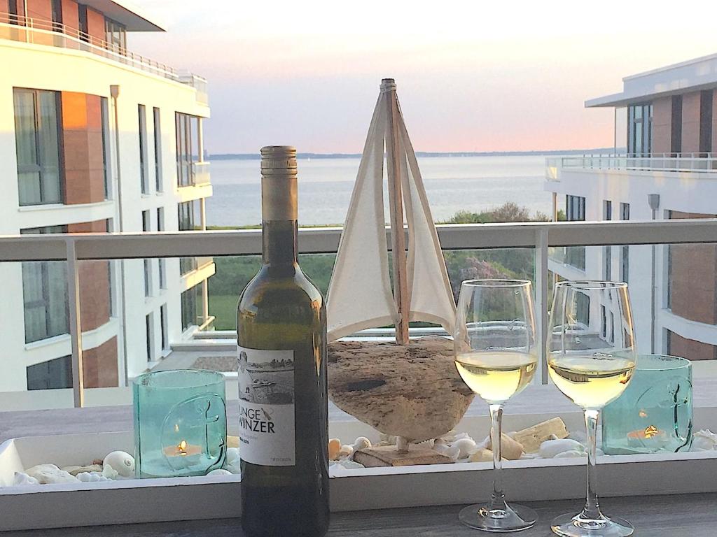 eine Flasche Wein und zwei Gläser auf dem Balkon in der Unterkunft Südkap C-10 in Pelzerhaken
