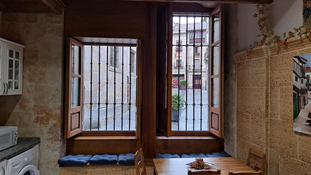 Cette chambre dispose de deux fenêtres, d'une table et de chaises. dans l'établissement LAS CATEDRALES De SALAMANCA, à Salamanque