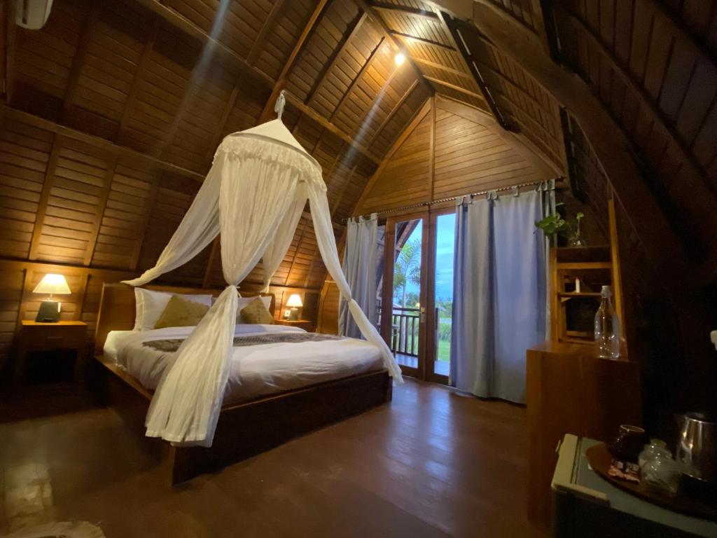 1 dormitorio con 1 cama con mosquitera en Kubu Bakas Guest House - CHSE Certified en Banjarangkan