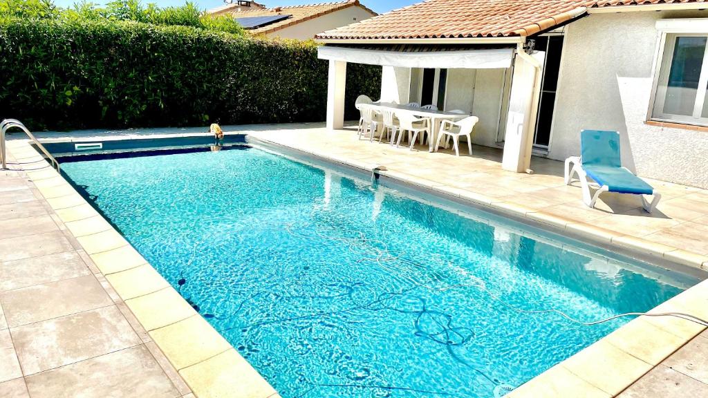 una piscina con una mesa y una silla azul en Maison d'une chambre avec piscine privee jardin clos et wifi a La Calmette, en La Calmette