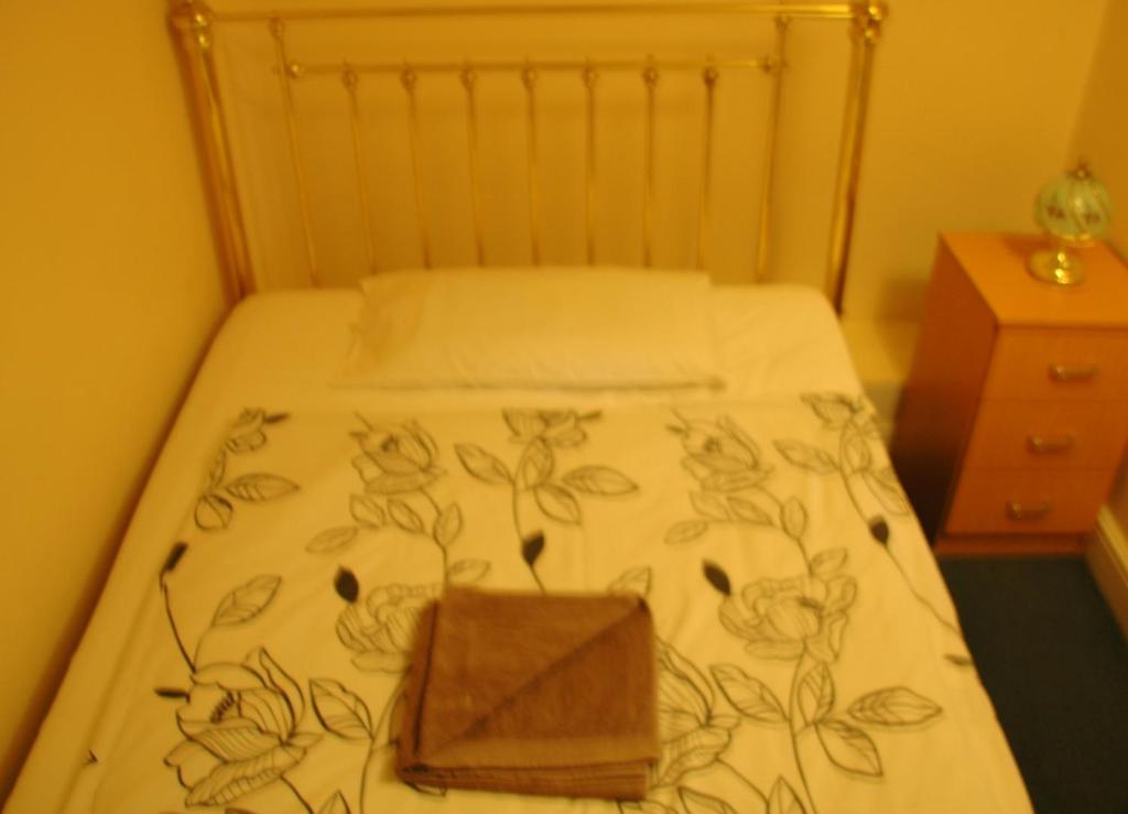a bed with a blanket with a wooden box on it at Revive Lodge in Hounslow