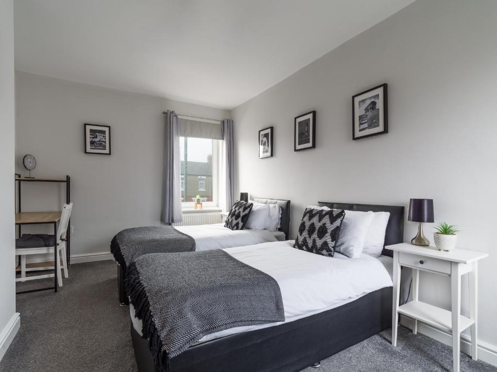 sypialnia z 2 łóżkami, biurkiem i oknem w obiekcie Haw thorn House - 2 bedroom, Ashington, Northumberland w mieście Ashington