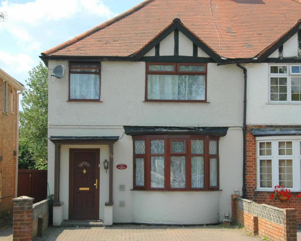 a white house with a brown roof at Revive Lodge in Hounslow