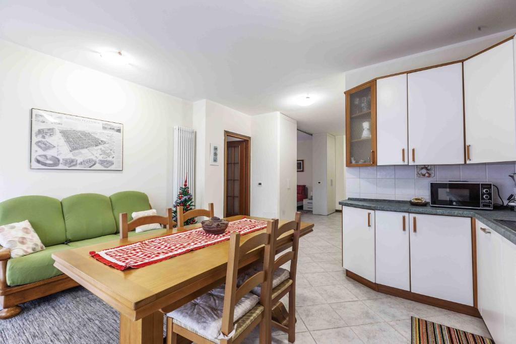 a kitchen and living room with a table and a green couch at Casa Alpina - Appartamento Aosta in Aosta