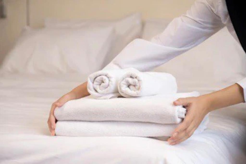 een vrouw met een stapel handdoeken op een bed bij Cosy Entire Apartment in WhiteChapel/Commercial Rd in Londen