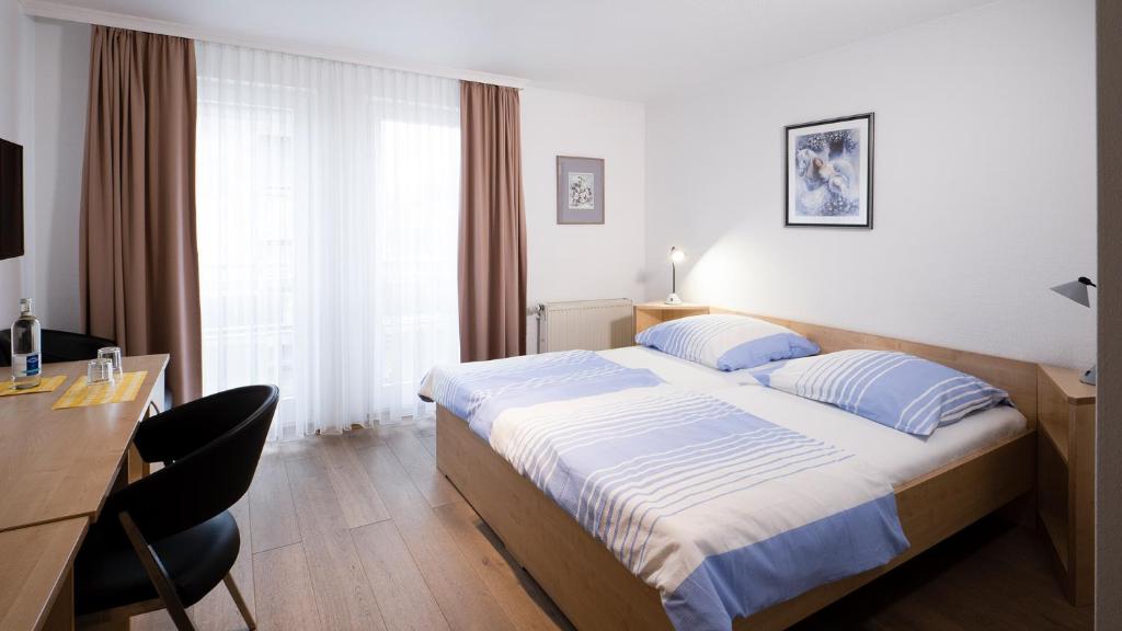 Habitación de hotel con cama, escritorio y mesa. en Brenzhotel Heidenheim, en Heidenheim an der Brenz