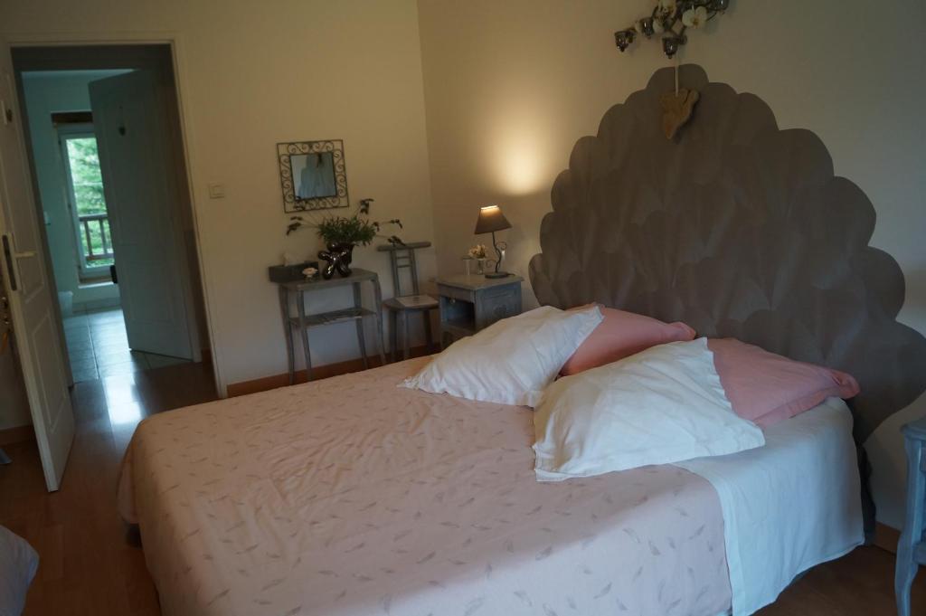 a bedroom with a large bed with pink and white pillows at chambre d’hôtes la jument grise in Lescheroux