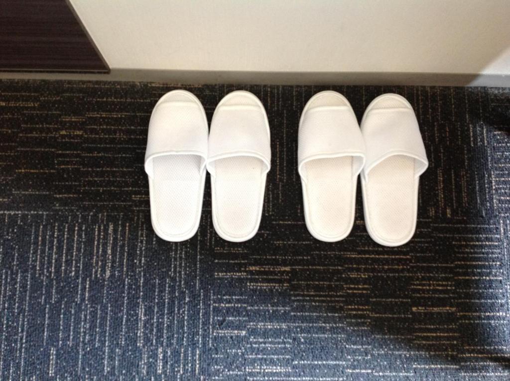 a row of white shoes sitting on a floor at Washington R&B Hotel Hachioji in Hachioji