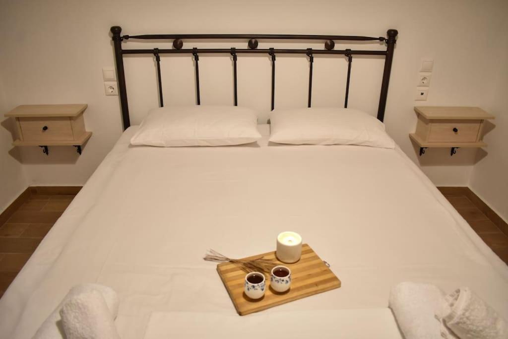 Una cama con una bandeja con dos vasos y una vela en Liberty's House, en Mouresi
