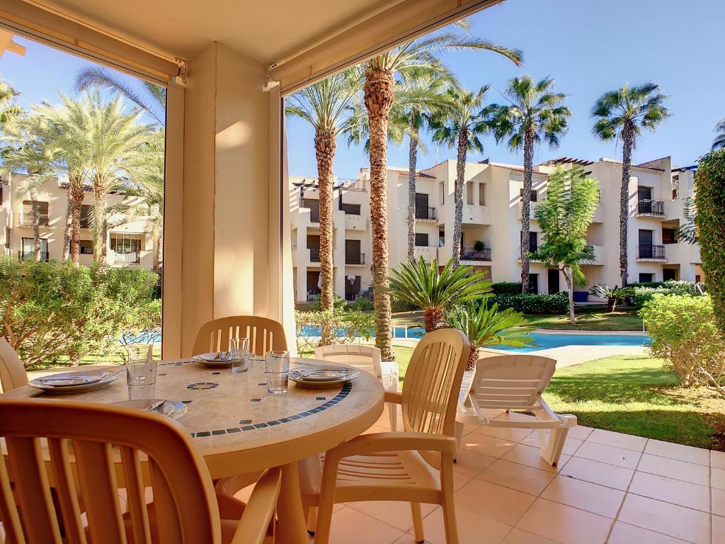 un patio con mesa, sillas y palmeras en Roda Golf Resort - 9309, en San Javier