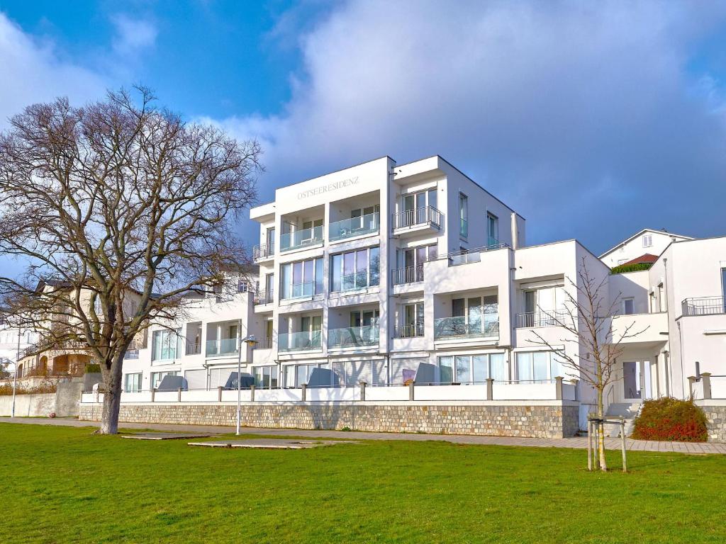 ein weißes Gebäude mit einem Baum davor in der Unterkunft Ostseeresidenz Sassnitz F548 WG 16 mit Kamin, Sauna, Meerblick in Sassnitz