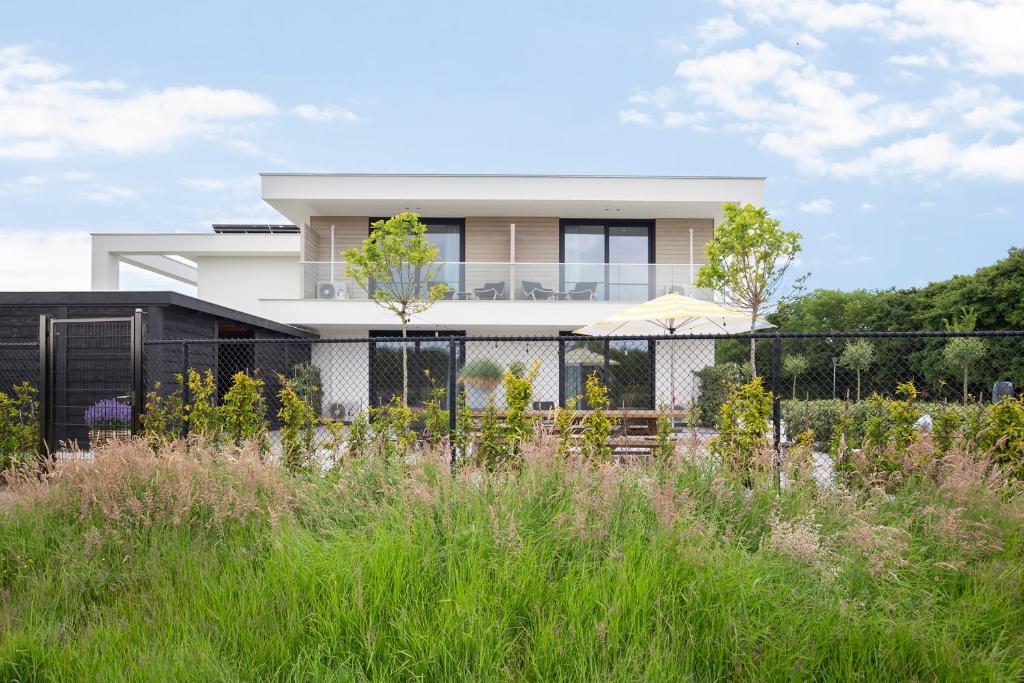 uma casa branca com uma cerca e um jardim em Hello Zeeland - Summum Suites em Domburg