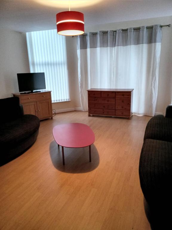 Sandringham House في ليفربول: غرفة معيشة مع طاولة حمراء وأريكة