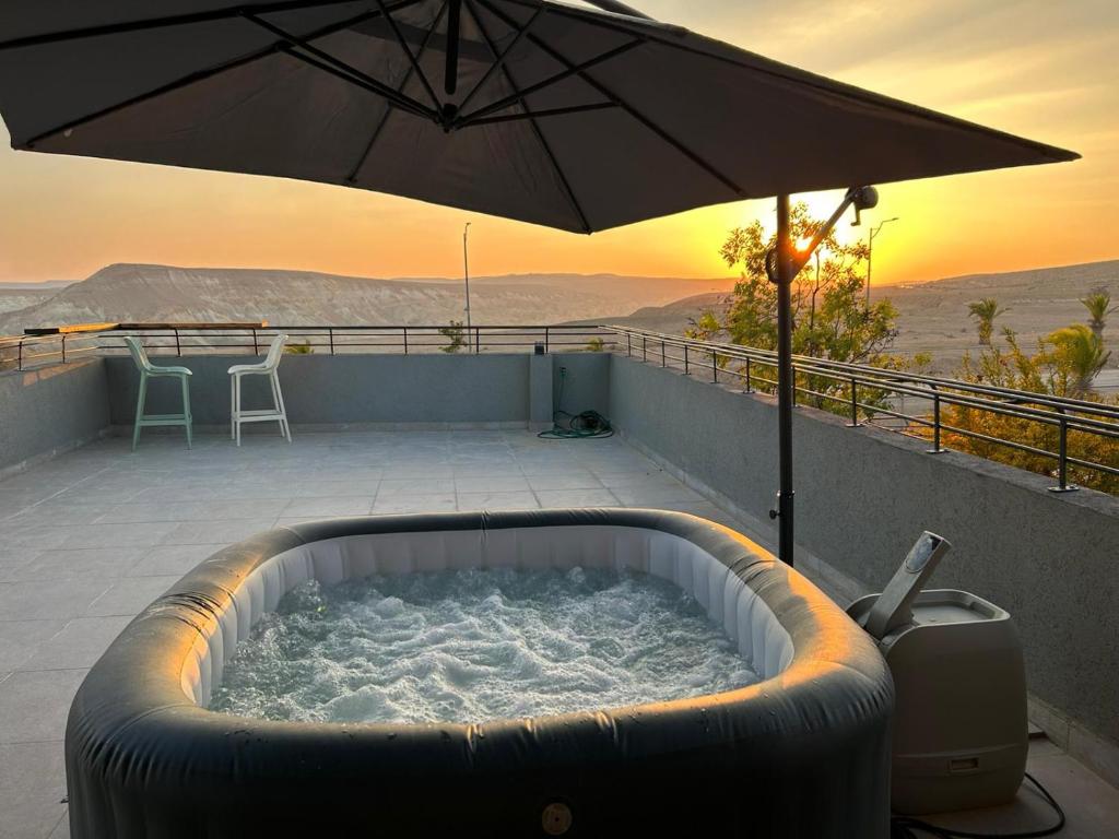 a hot tub on a patio with an umbrella at נס הבריאה in Midreshet Ben Gurion