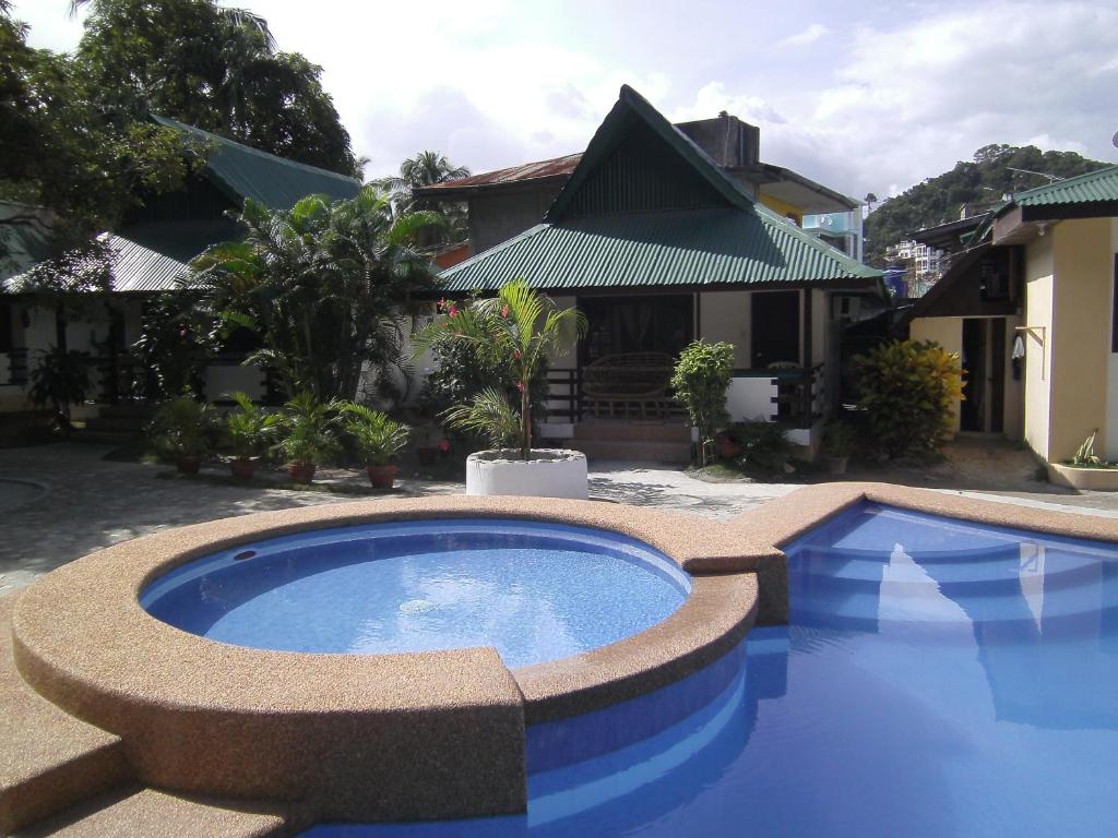 a large blue pool in front of a house at Seashore Beach Resort in Puerto Galera