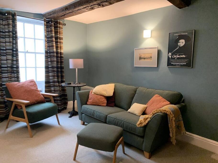 a living room with a green couch and a chair at Smuggler's Cottage in Deal