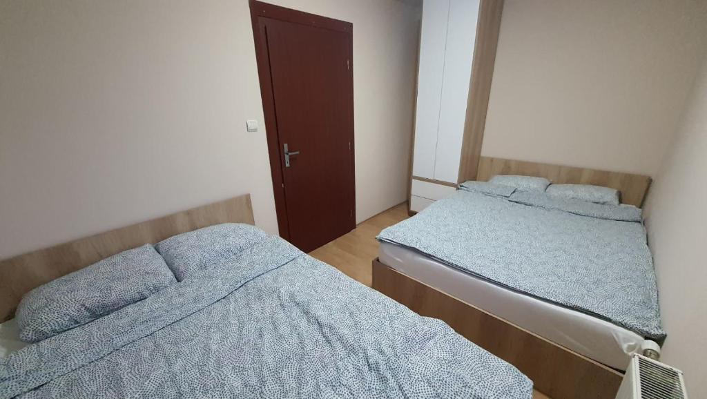 a bedroom with two beds and a door at Zlatibor Apartman Kraljev trg in Zlatibor