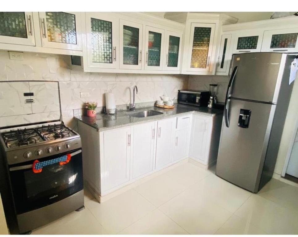 a kitchen with a stainless steel refrigerator and white cabinets at Oasis de Paz 2.1 in Jarabacoa