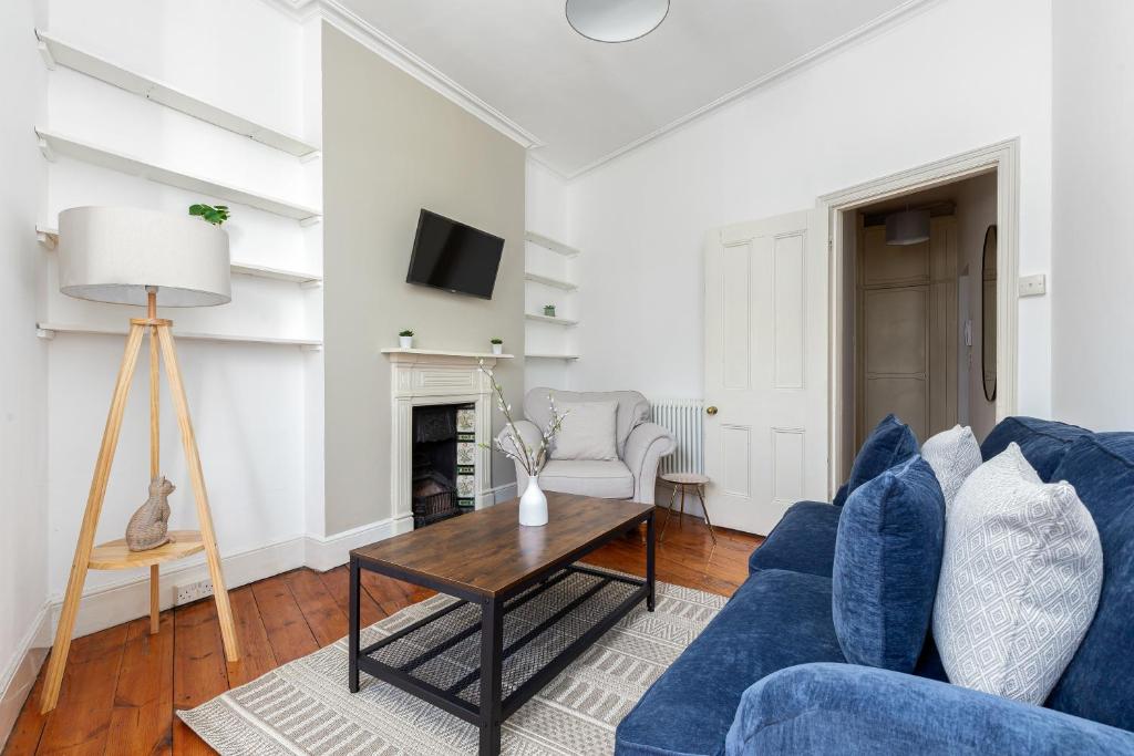The Goldhawk Road Apartments في لندن: غرفة معيشة مع أريكة زرقاء وطاولة