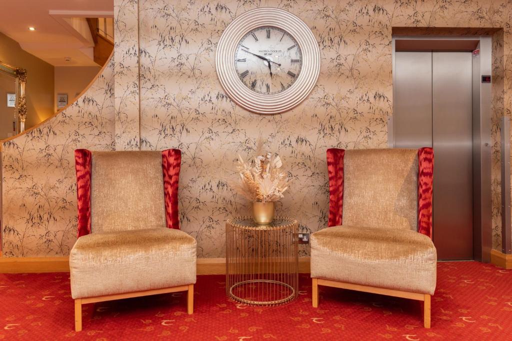 two chairs and a clock on a wall at Tara Lodge in Belfast