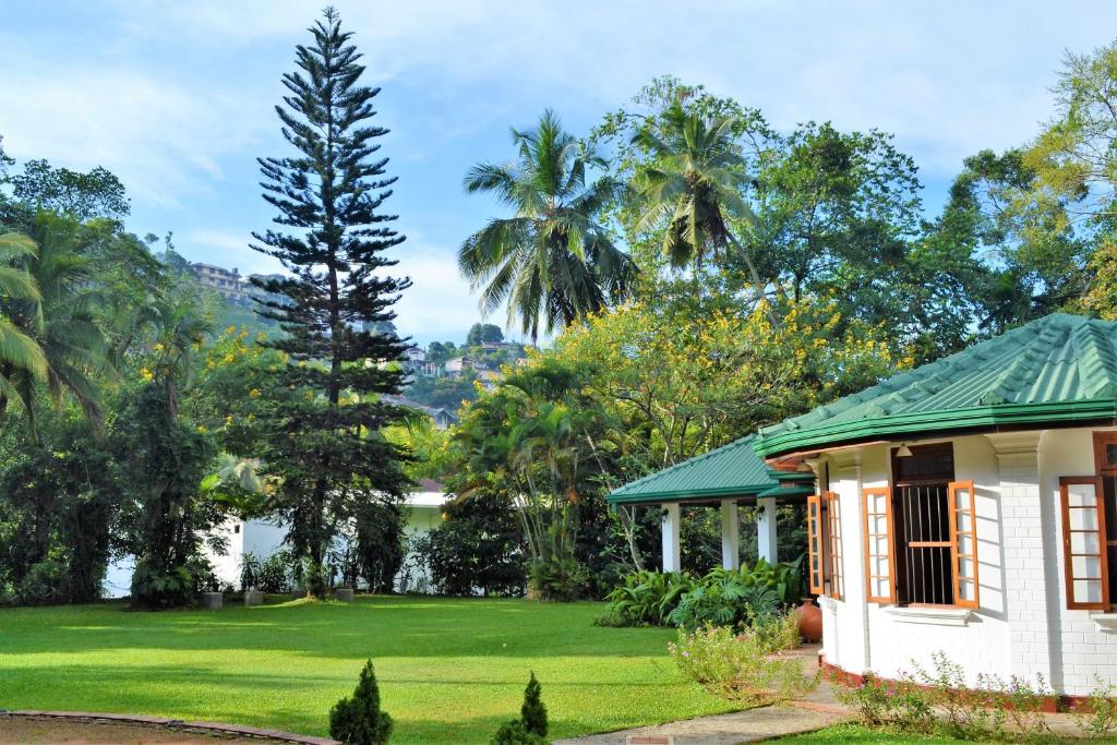 a white house with a green roof and a yard at Sweet Cinnamon Kandy in Kandy