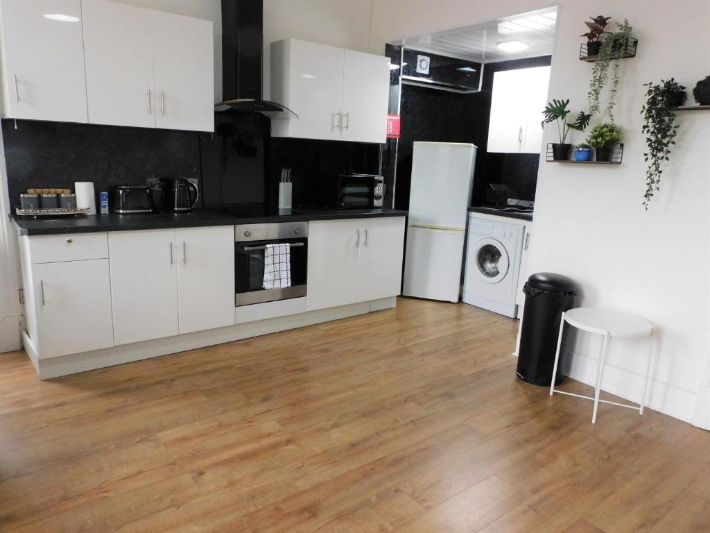 a kitchen with white cabinets and a wooden floor at Comfortable 4 bed Apt in Paisley Next to Station in Paisley