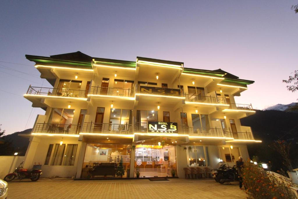 un gran edificio blanco con luces encendidas en Hotel NSB Manali, en Manali