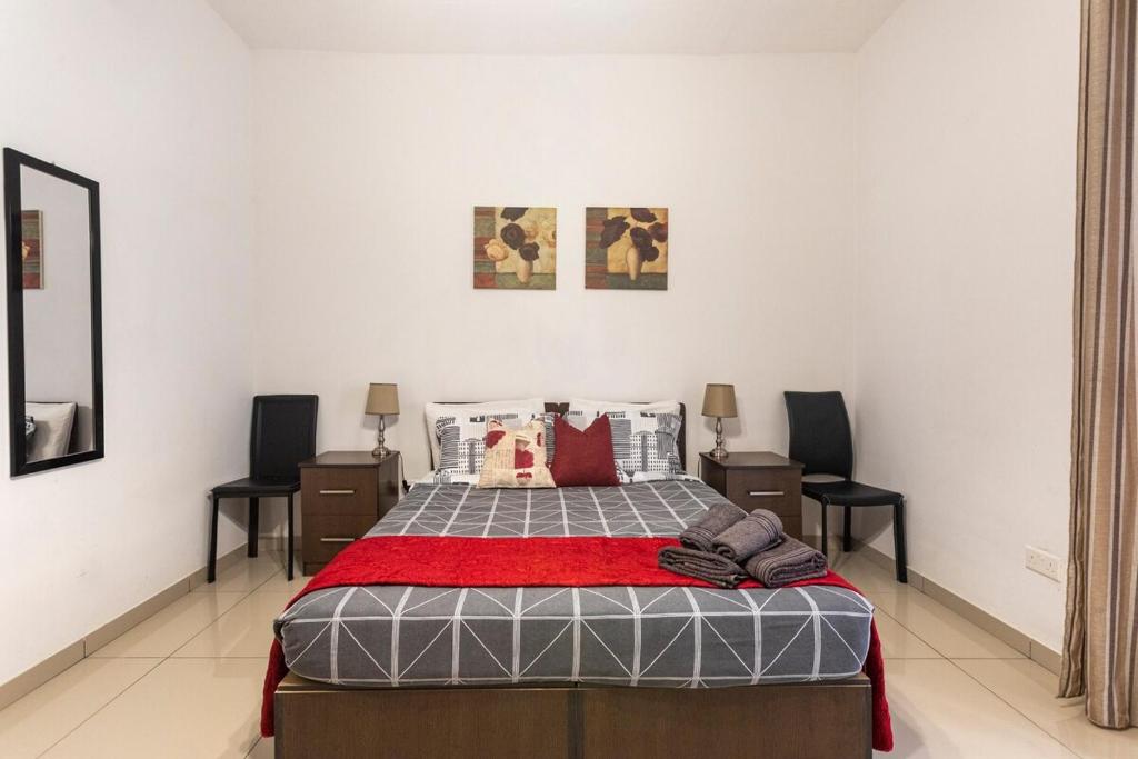 een slaapkamer met een bed en 2 stoelen bij Superbly Located Cosy 2-Bedroom Apartment Valletta in Valletta