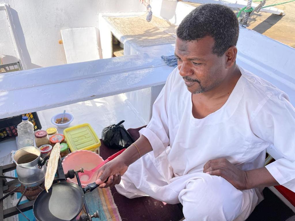 a man sitting on a table stirring a pot at My Dream Nile Felucca in Aswan