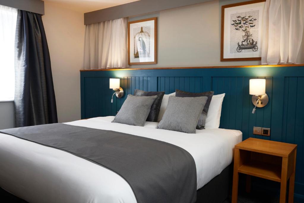 um quarto com uma cama grande e uma parede azul em Holmfield Arms by Greene King Inns em Wakefield