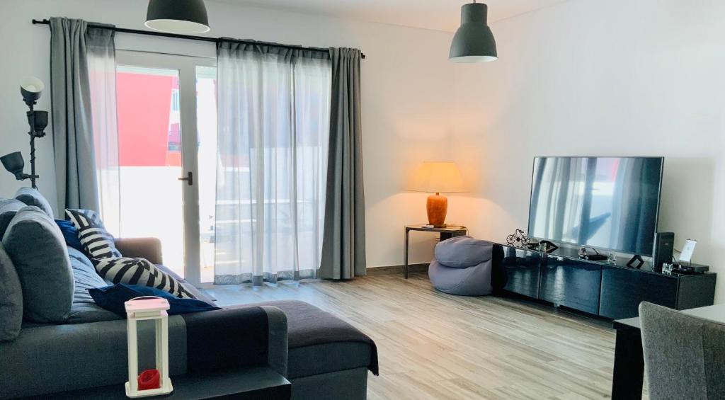 Una sala de estar con un sofá y un televisor de pantalla plana. en Supertubos - Peniche - Consolação, en Peniche