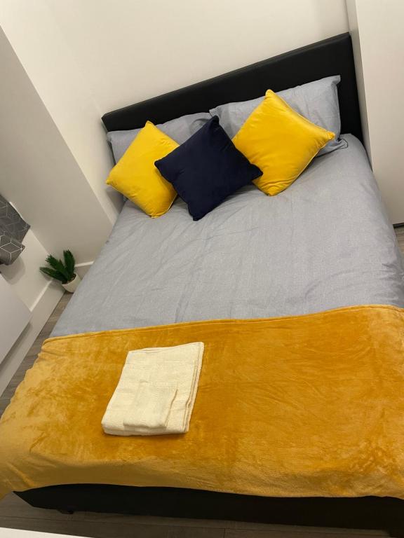 a large bed with yellow and blue pillows at London Studios in BR54LT in Saint Mary Cray