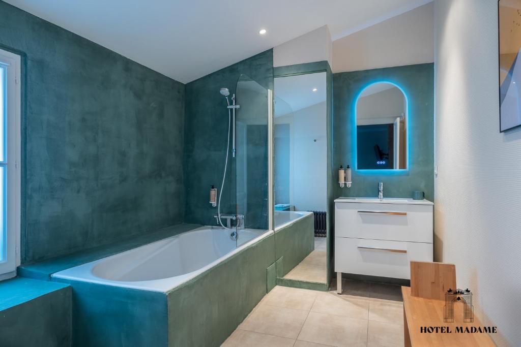 La salle de bains est pourvue d'une grande baignoire et d'un lavabo. dans l'établissement Hôtel Madame, à Bordeaux