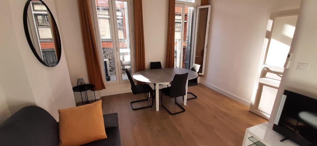 a living room with a table and chairs and a mirror at T2 neuf tout équipé, climatisé in Marseille