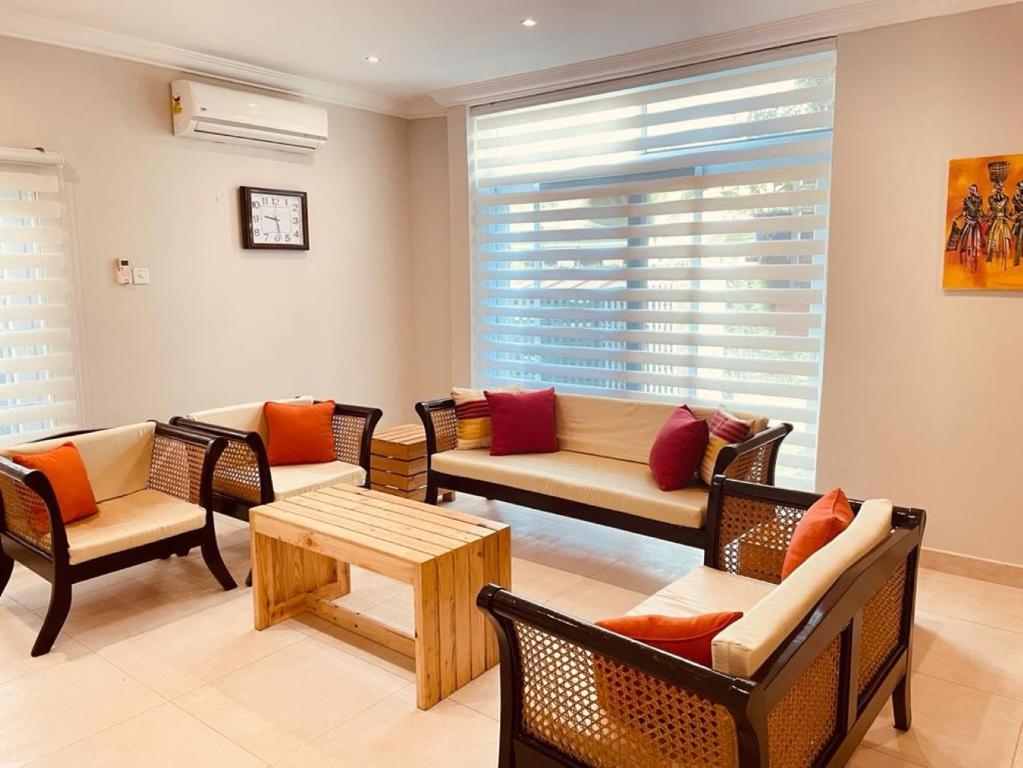 sala de estar con sillas, sofá y mesa en Green Court Serviced Apartments en Accra