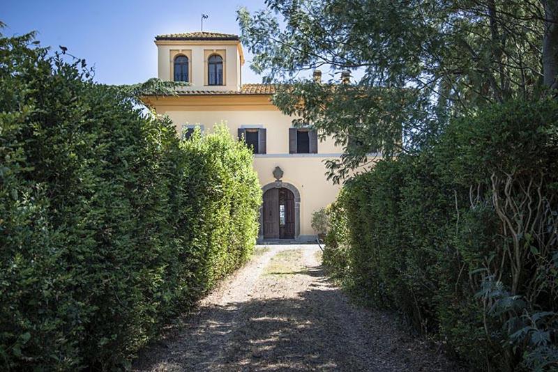 ein großes gelbes Haus mit einem Turm darüber in der Unterkunft Agriturismo Sensi in Tuscania