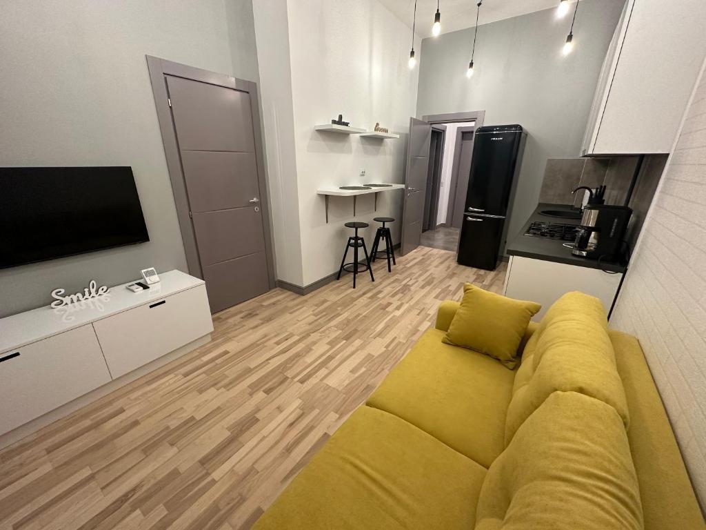 uma sala de estar com um sofá amarelo e uma cozinha em Mojo-Jojo / a funky stay em Iaşi