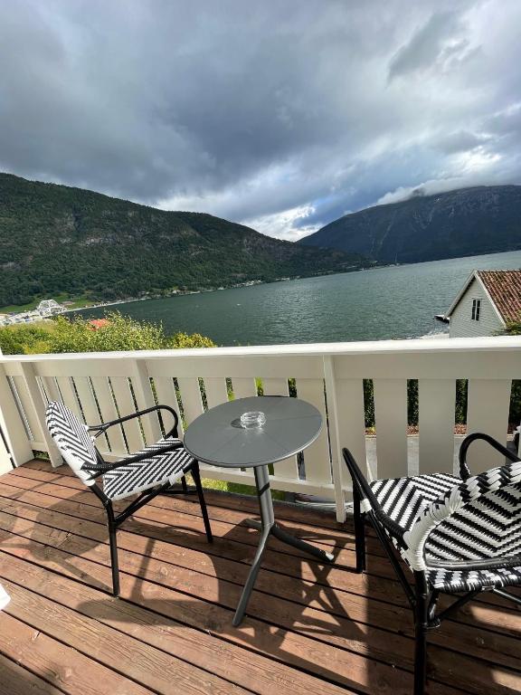 a table and chairs on a deck with a view of a lake at Hofslund Apartments in Sogndal