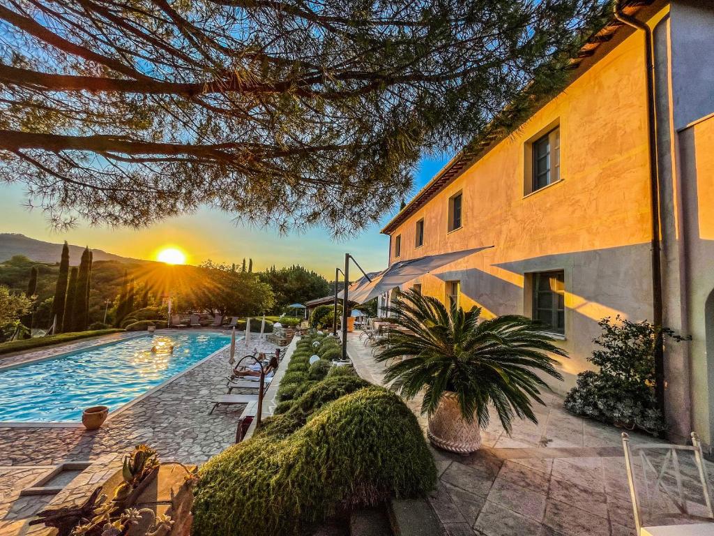 a building with a swimming pool with the sunset in the background at Countryhouse Villa Rey in Panicale