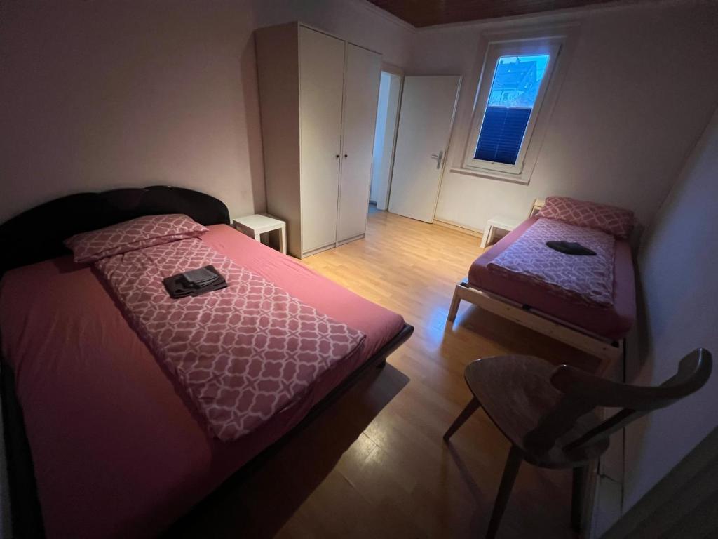 a bedroom with two beds and a chair and a window at Siegen Achenbach 2 in Siegen